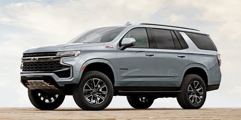 Chevy Tahoe stands parked on open ground, showcasing its rugged design and robust presence